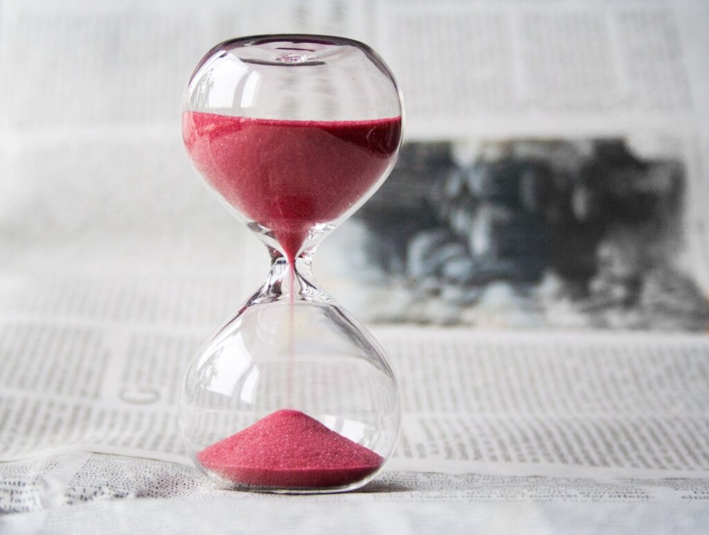 Ampulheta de vidro com areia vermelha, simbolizando que o tempo passa e os hábitos saudáveis que prometemos muitas vezes não são criados.